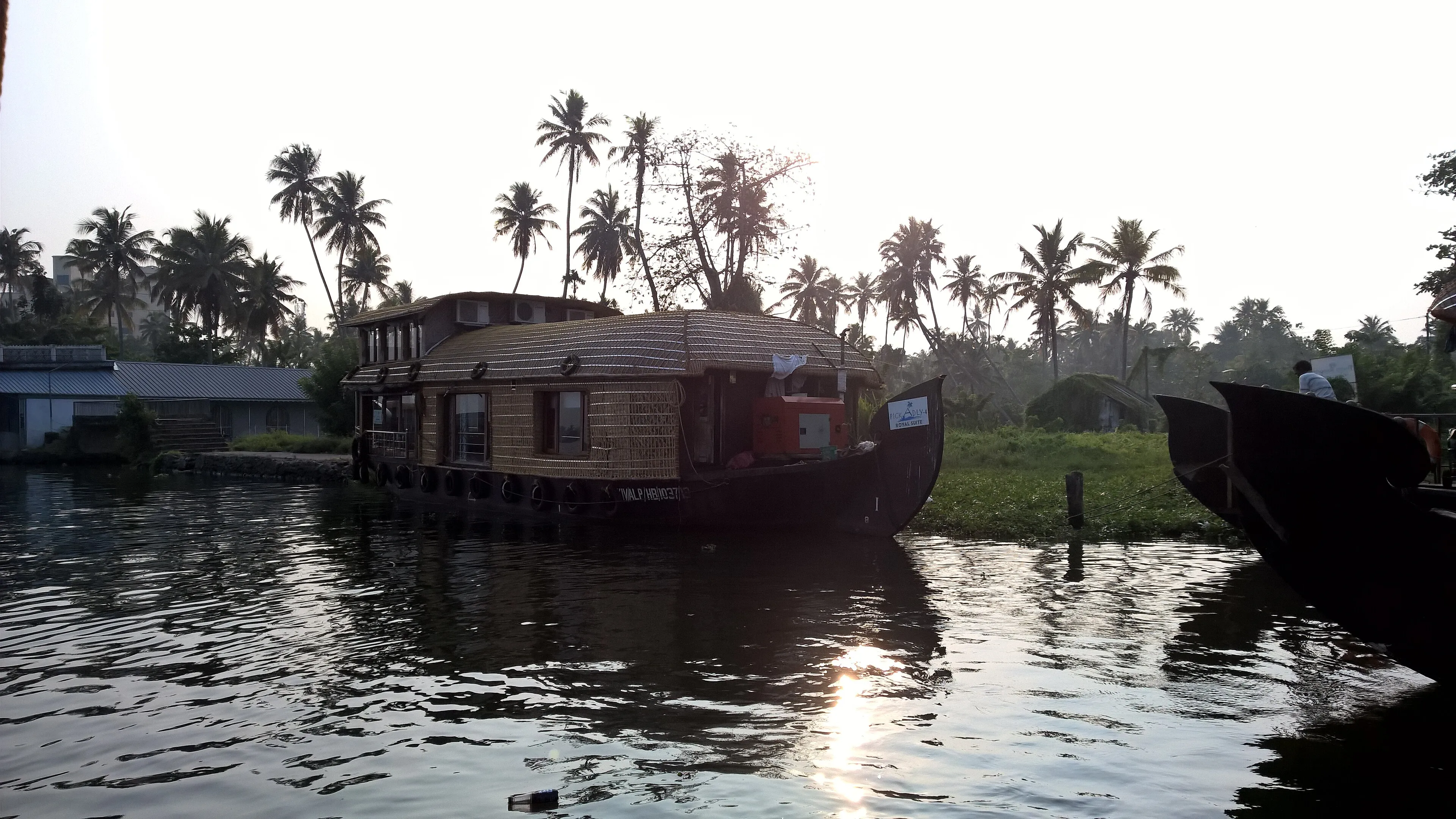 Alleppey backwater sunset reflected on still water with a silhouetted houseboat